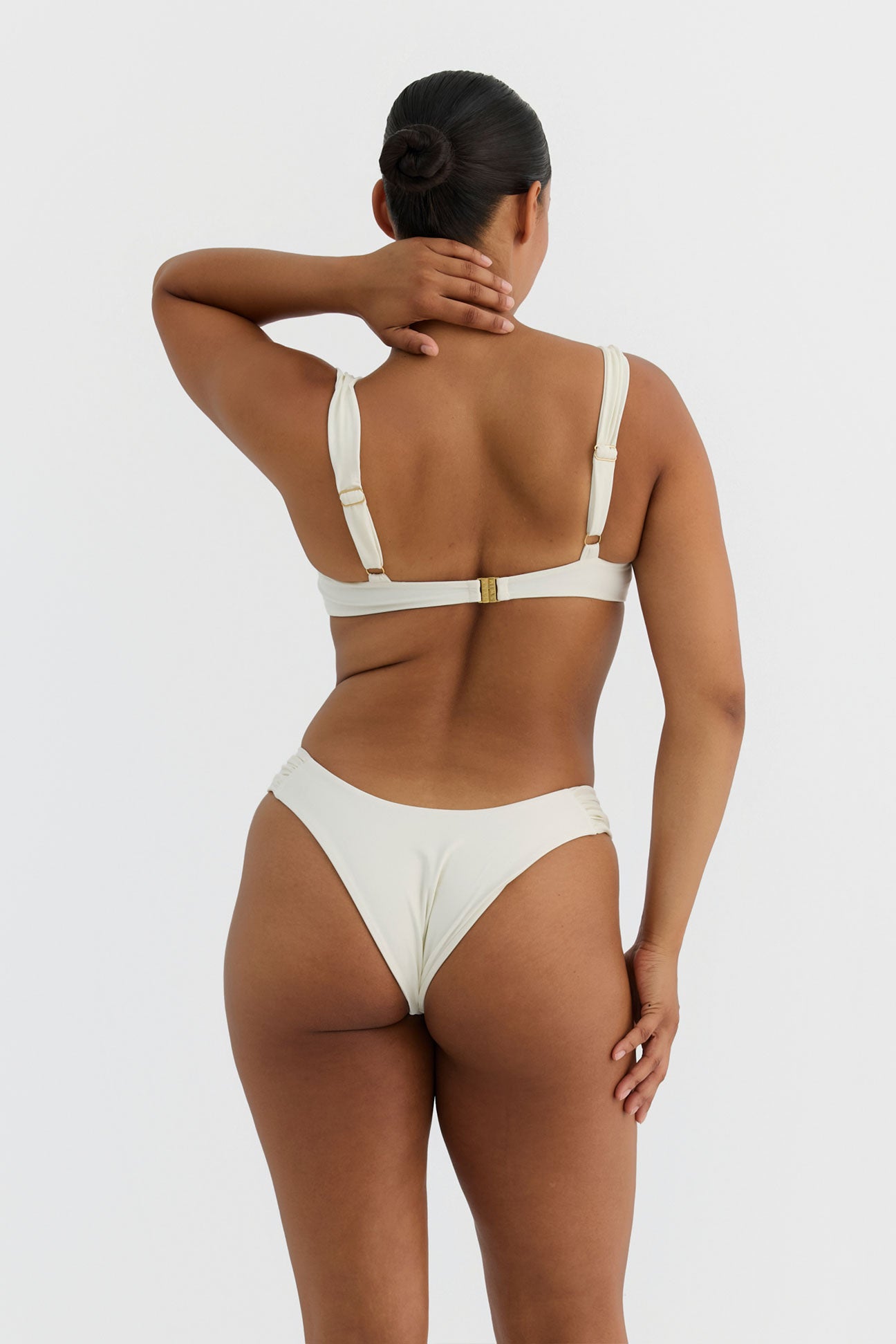 Woman wearing an ivory bikini against a plain background