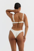 Woman wearing an ivory bikini against a plain background