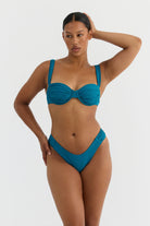 Woman wearing a teal bikini against a white background