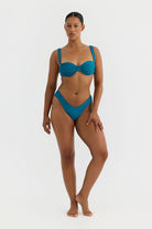 Woman wearing a teal bikini on a white background