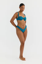 Woman wearing a teal bikini on a white background