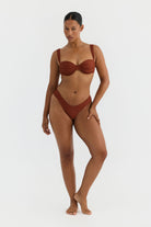 Woman wearing a terracotta swimsuit on a white background