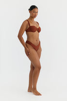 Woman wearing a terracotta bikini on a white background