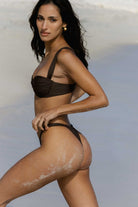 Woman wearing a chocolate brown bikini against a neutral background