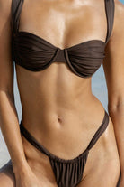 Person wearing a brown bikini against a blurred natural background