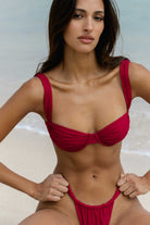 Woman wearing a magenta bikini against a neutral background