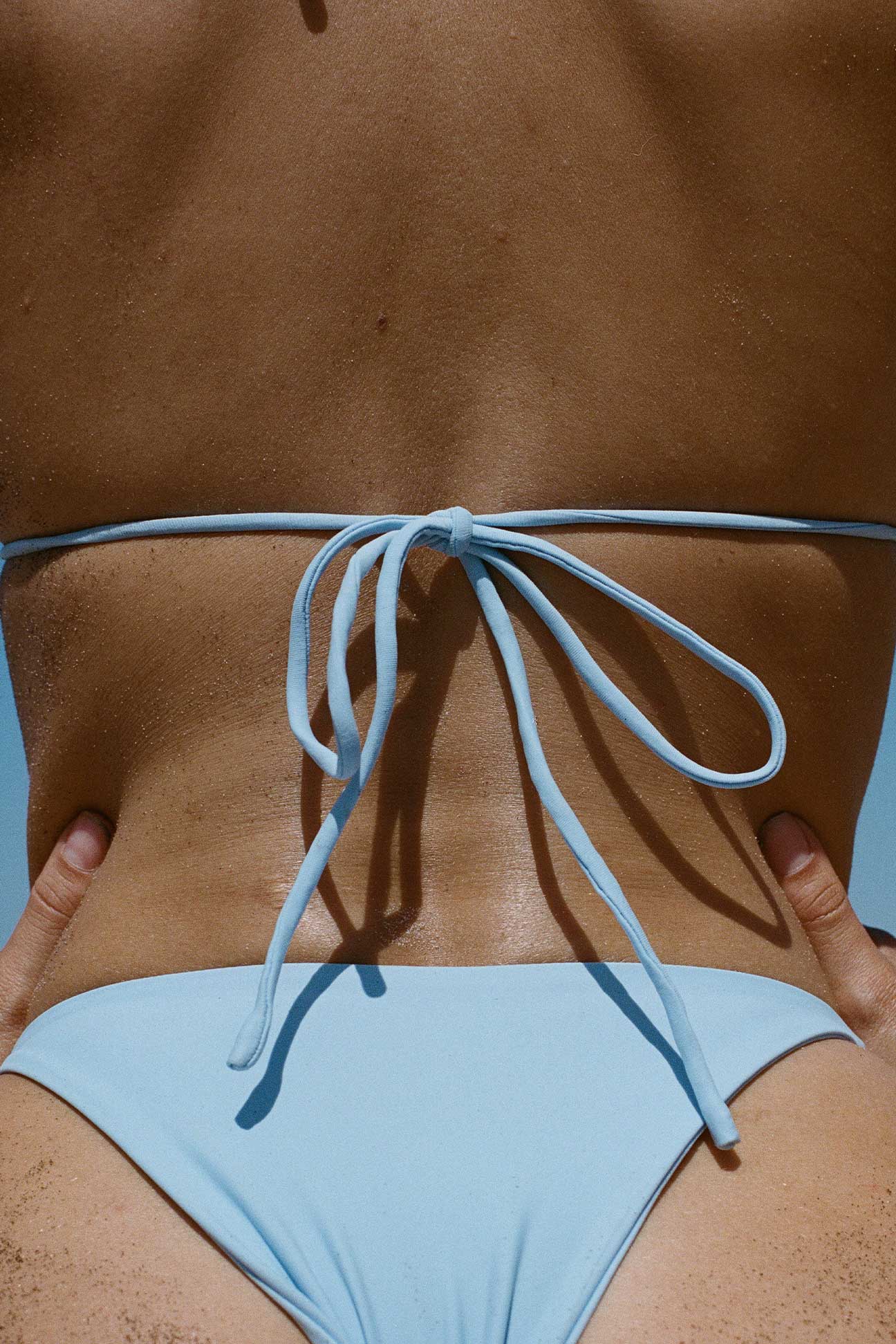 Light blue bikini bottom with a tie back on a person against a neutral background
