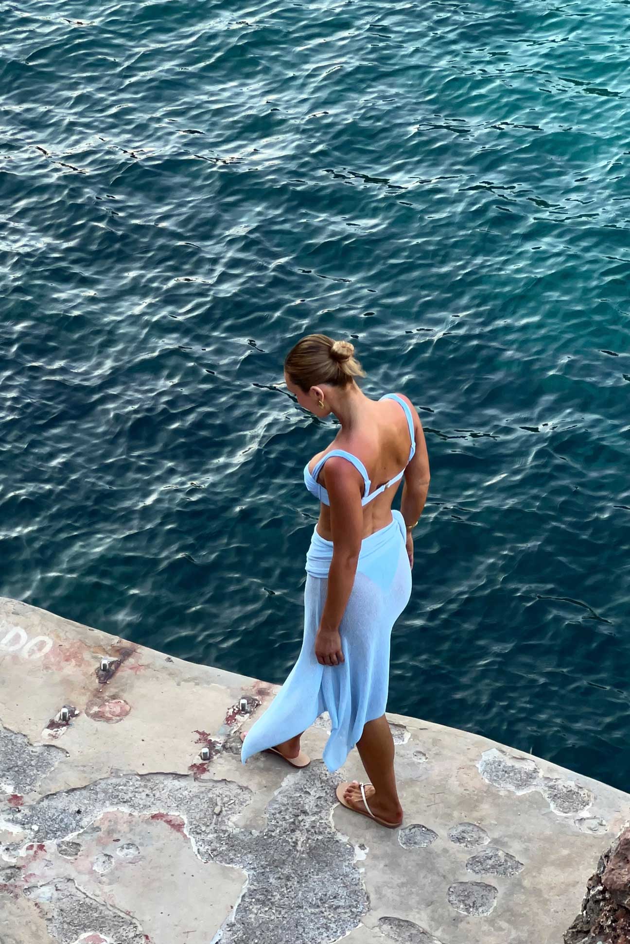 Woman in soft blue bikini walking near ocean