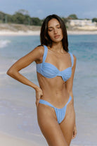 Woman wearing a blue bikini standing on a beach