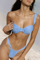 Woman wearing a blue bikini against a neutral background