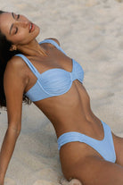 Woman in a light blue bikini lying on sand