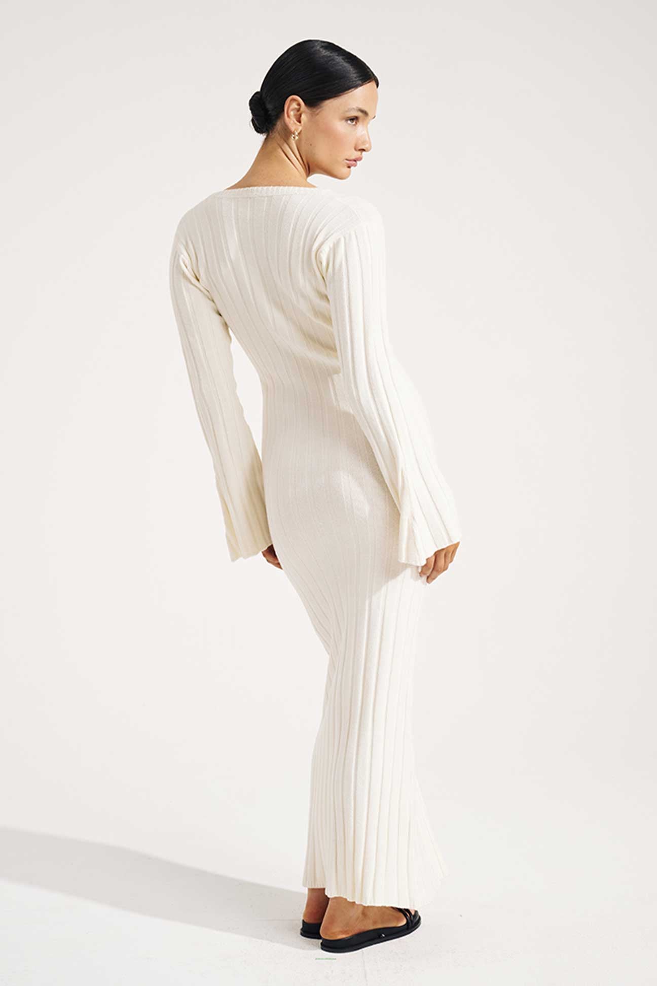Woman wearing a long, light-colored dress on a white background