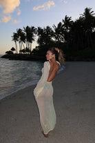 Woman in a yellow dress standing on a beach with palm trees in the background