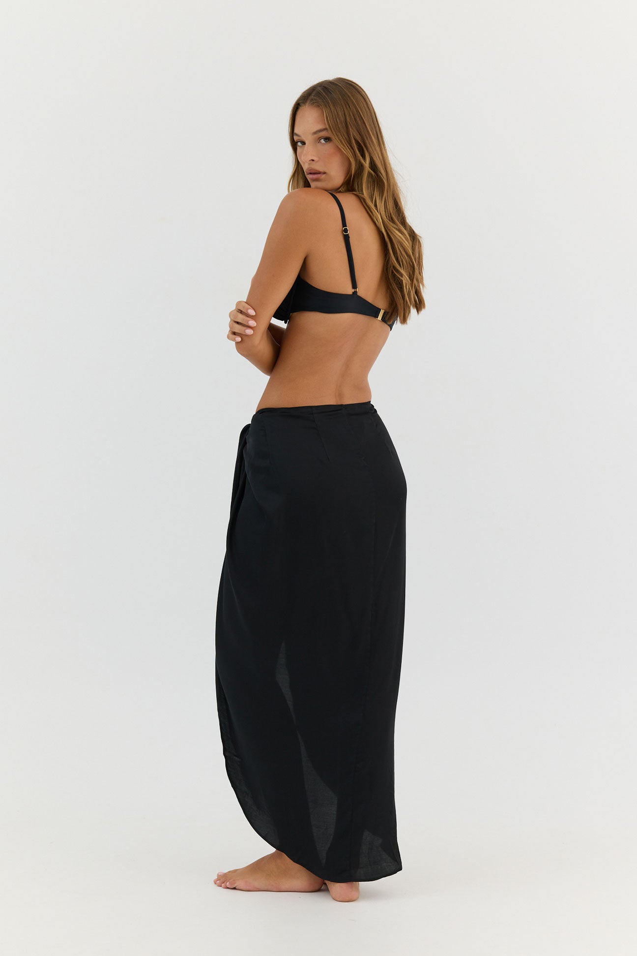 Woman wearing a black bikini and long black skirt on a white background