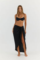Woman wearing a black bikini and matching wrap skirt on a white background