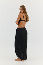 Woman wearing a black bikini and long black skirt on a white background