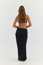 Woman wearing a black bikini and wide-leg pants on a white background