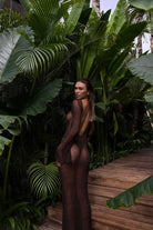 Woman in a sheer dress standing amidst tropical plants