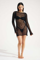 Model wearing a black sheer dress on a white background