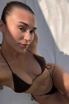 Woman wearing a brown bikini against a neutral background