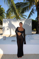 Woman in a black dress standing in front of palm trees