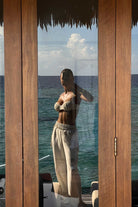 Woman standing by a wooden structure with a view of the ocean.