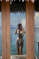 Person taking a mirror selfie in a swimsuit with ocean view
