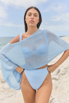 Woman wearing a light blue poncho on a beach