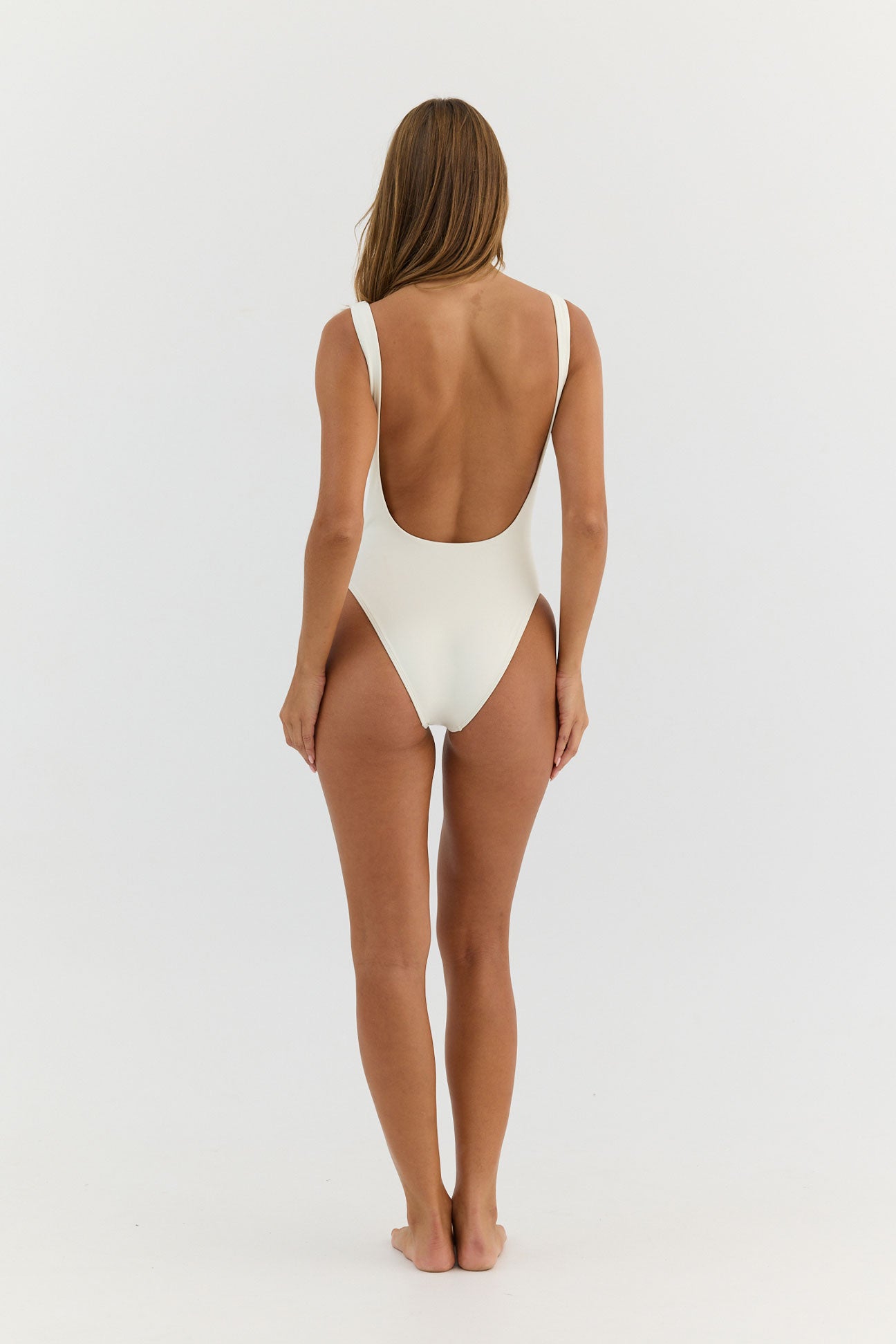 Woman wearing a white one-piece swimsuit on a light gray background