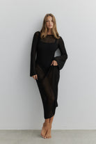 Woman wearing a black dress against a plain background