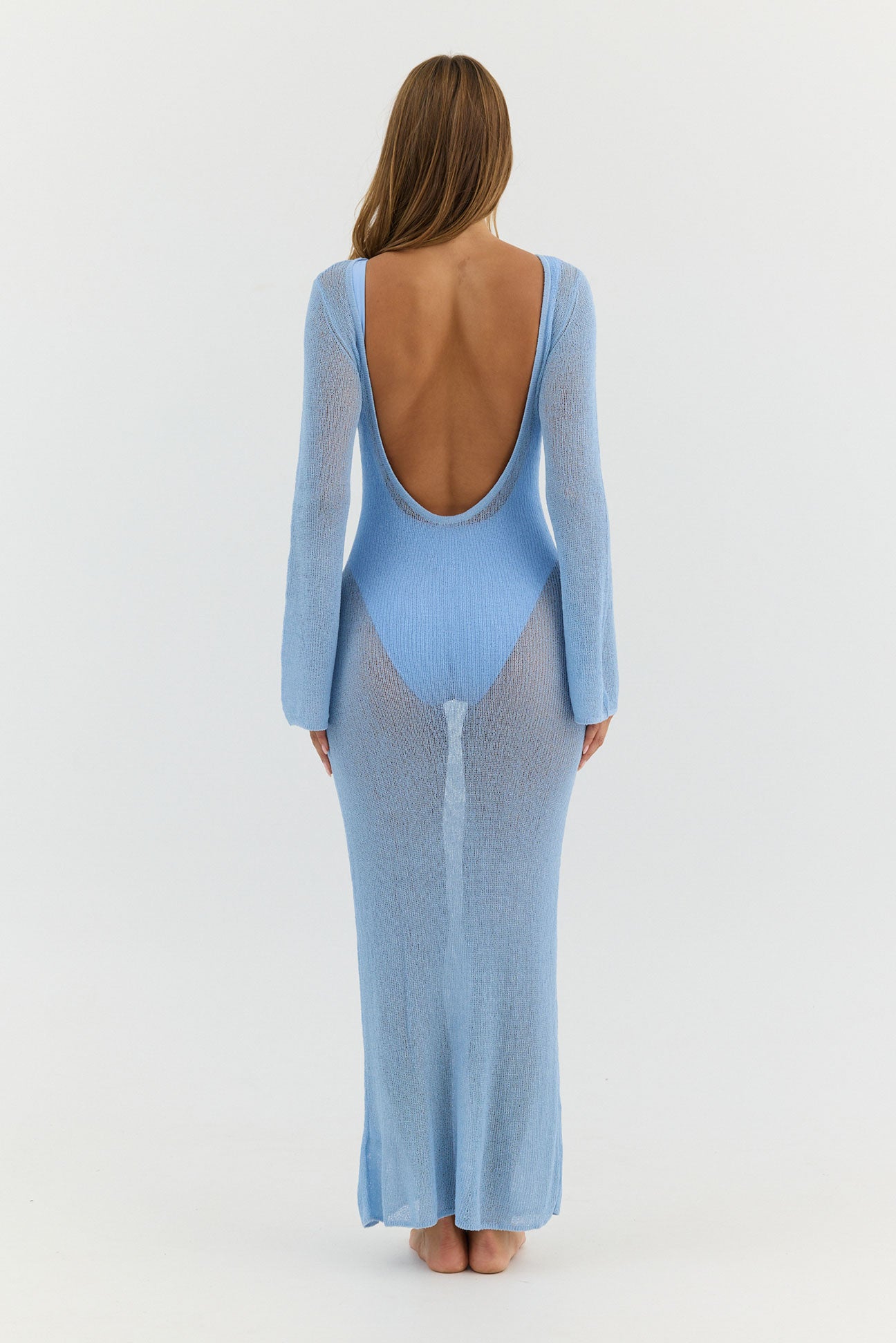 Woman wearing a light blue dress with a backless design on a white background
