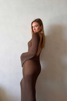 Woman wearing a brown dress against a plain background
