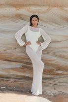Woman wearing a white dress against a textured stone wall
