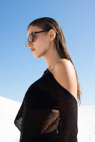 Woman wearing sunglasses and a black top against a clear blue sky