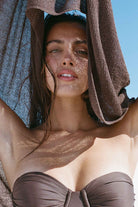 Woman with a brown poncho over her head, sunbathing outdoors
