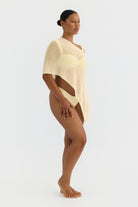 Woman wearing a butter yellow knit poncho on a white background