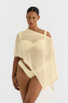 Woman wearing a butter yellow knit poncho on a white background