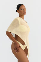 Woman wearing a light-colored swimsuit cover-up against a plain background