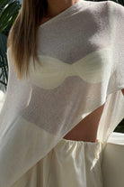 Person wearing a white poncho shawl top.