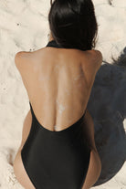 Person wearing a black swimsuit on a sandy beach