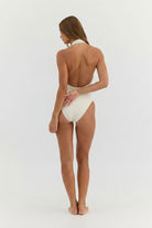 Woman wearing a white swimsuit on a light gray background