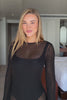 Person wearing a black dress against a plain background.