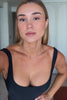 Woman wearing a black swimsuit on a plain background
