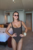 Person wearing a brown swimsuit on a plain background