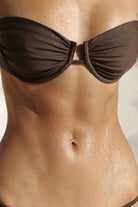Brown bikini top worn by a person with a neutral background