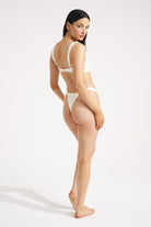Woman wearing an ivory bikini on a plain background