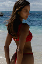 Woman in a red bikini standing on a beach with ocean in the background