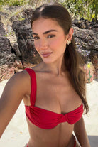 Woman in a red bikini standing against a rocky background
