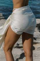 Person wearing a white skirt with a blurred background of water and rocks
