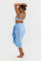Woman wearing a light blue bikini and sarong on a white background